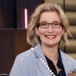 Person holding flowers, wearing blazer.